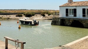 Un bateau était amarré près d’un bâtiment blanc doté d’un toit en tuiles, d’un pont de pierre et d’une plage de sable.