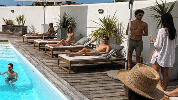 Un espace aménagé au bord de la piscine, avec des chaises longues et des parasols, une piscine et une terrasse en bois.