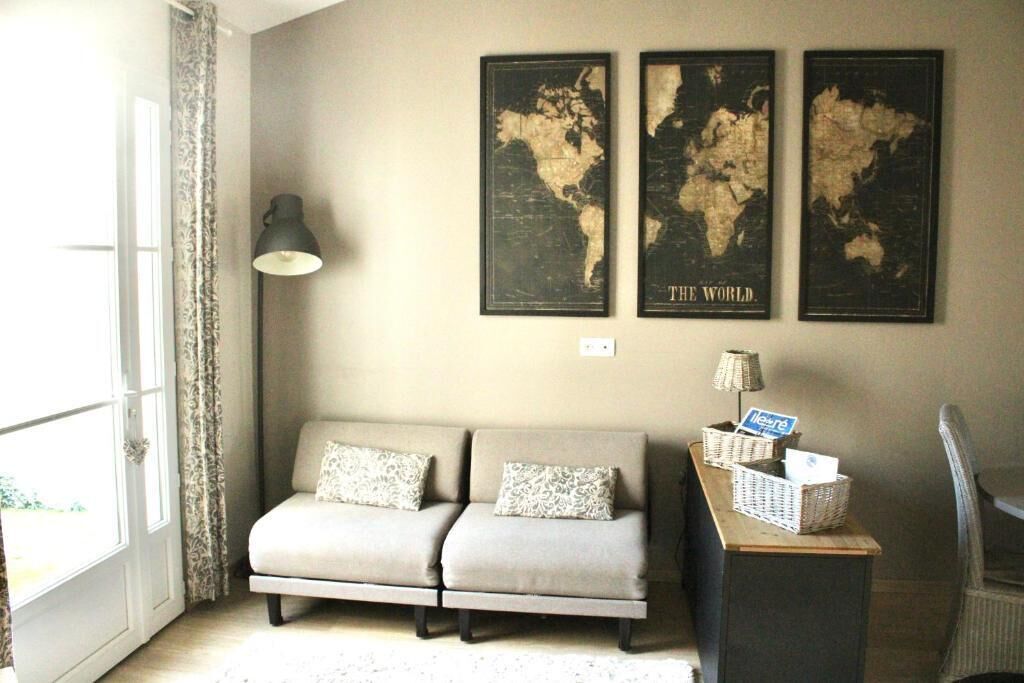 Une pièce avec un canapé, une lampe et trois cartes du monde accrochées au mur.