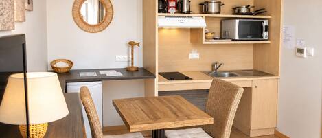 A compact kitchen with a dining area, equipped with a microwave, stove, and a sink.