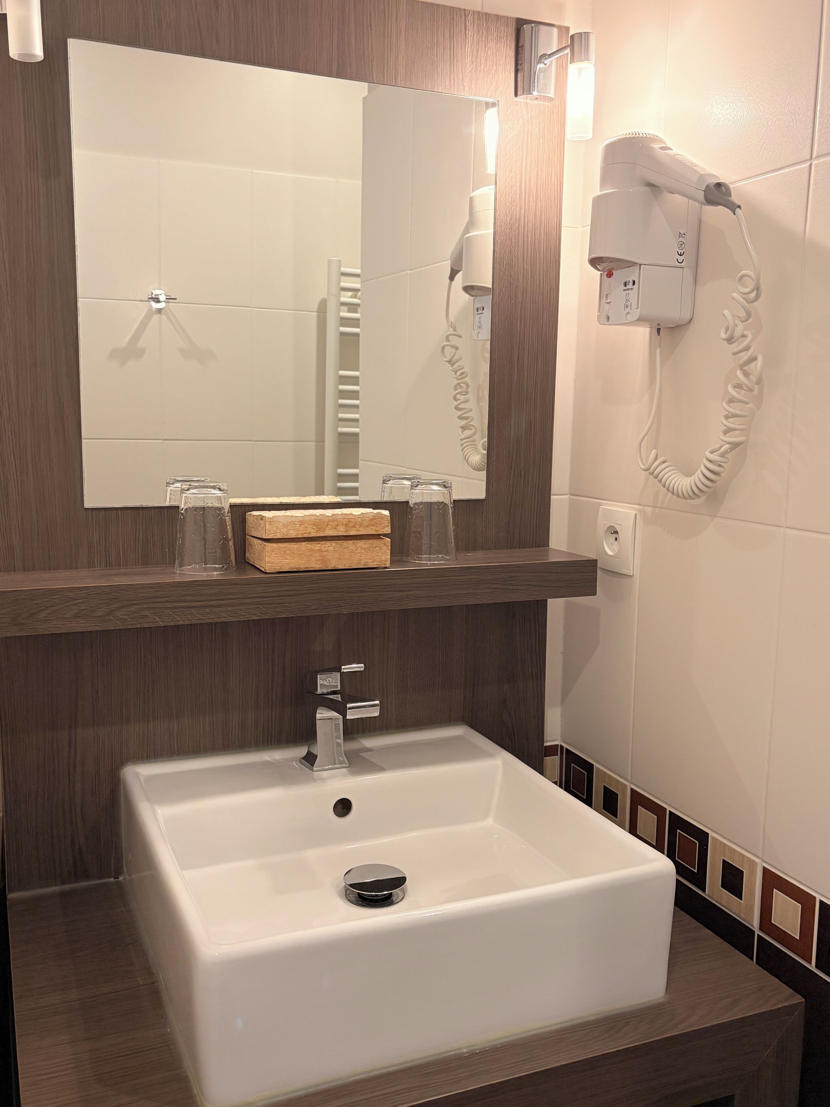 A bathroom with a white sink, a mirror, a hairdryer, and a towel rack.