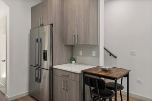 A compact kitchen with a built-in refrigerator, a small countertop, and a wooden table with chairs. - Brand New 2BR Townhome in Fremont | Rooftop Patio (Seattle)