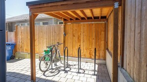 Un espace extérieur abrité, doté d’une clôture en bois, d’un support à vélos et d’une poubelle de recyclage.