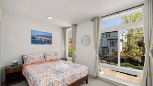 Une chambre à coucher avec un grand lit, une table de chevet, une fenêtre avec des rideaux et un grand miroir rond fixé au mur.
