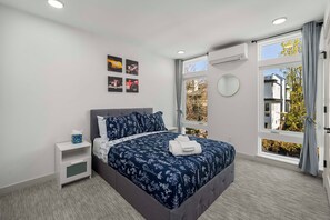 Ein Schlafzimmer mit Bett, Nachttisch und einem Fenster mit Blick.