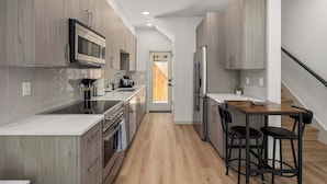 Une cuisine moderne avec des meubles en bois, des appareils en acier inoxydable et un îlot central doté de tabourets de bar.