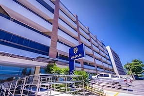 Um edifício moderno com um letreiro chamativo 'ColdFlat', vários andares e uma área de estacionamento com veículos.