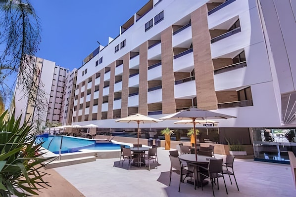 Een hotel met een zwembad, terras en een modern architectonisch ontwerp.