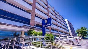 A modern building with a prominent 'ColdFlat' sign, multiple floors, and a parking area with vehicles. - Gold Flat - Bela Vista (João Pessoa)