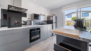 A modern kitchen with a built-in oven, microwave, and refrigerator. - Ty An Heol Cottage: Private Terrace & Wi-Fi in Le Conquet, Brittany (Le Conquet)