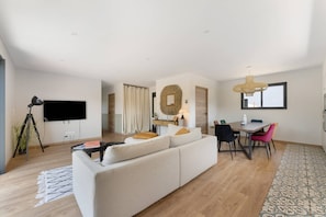 A modern living room with a sofa, dining table, and chairs. - Villa 'Laross' with Private Garden and Wi-Fi (Gujan-Mestras)