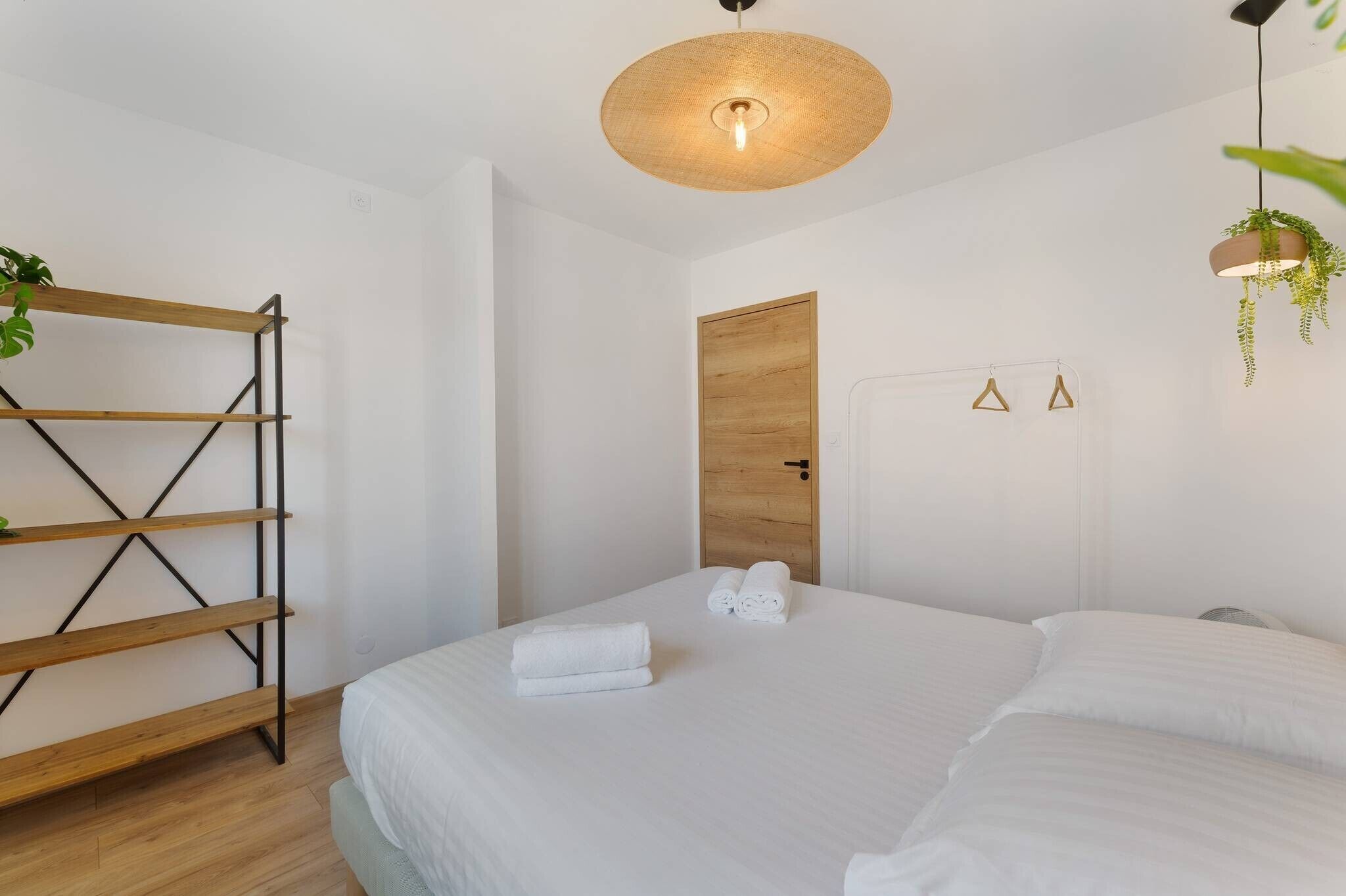 Una habitación de hotel con cama, escalera de madera, planta colgante y lámpara fijada a la pared.
