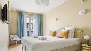 Una habitación de hotel con una cama, una silla, un televisor y una lámpara.