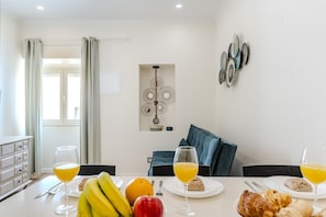 A dining area with a table set for breakfast, including fruits, pastries, and glasses of orange juice. - #378 Cozy Corner | City & Beach Escape (Albufeira)
