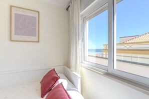 A room with a bed, a window with a view of a building, and a framed artwork on the wall. - #380 The Sea View Haven | Albufeira (Albufeira)