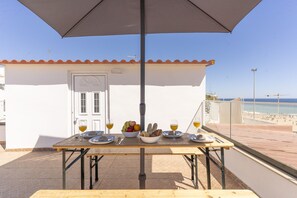 Une table avec de la nourriture et des boissons, placée sur un balcon donnant sur une plage.