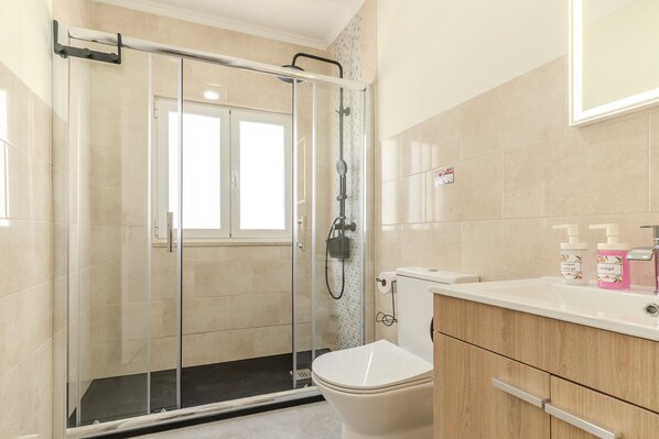 Une salle de bain avec une douche à parois de verre, des toilettes et un meuble-lavabo avec un miroir.