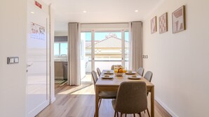 Ein Essbereich mit Tisch für vier Personen, eine Küche im Hintergrund und ein Balkon mit Blick.