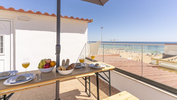 Ein Balkon mit Tisch für zwei Personen, einer Obstschale und einem Weinglas.