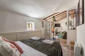 Une chambre avec un lit, une fenêtre, une télévision et un coin repas.