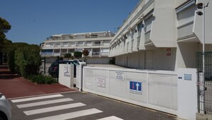 A multi-story residential building with balconies, a gated entrance, and a pedestrian crossing. - La Frégate by Interhome (Port Camargue)