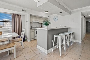 Eine moderne Küche mit einer zentralen Kochinsel, Barhocker und einem Essbereich mit Tisch und Stühlen.