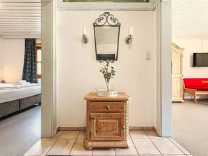 A room with a bed, a wooden console table with a vase, a wall-mounted mirror, and a television. - Bernkogel by Interhome (Saalbach-Hinterglemm)