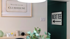 Une enseigne d’accueil encadrée, un panneau de signalisation, un luminaire, une plante et une table avec divers objets.