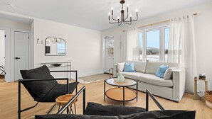 Un salon moderne comprenant un canapé, une table basse, un fauteuil et un lustre.