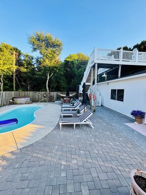 Un espace aménagé au bord de la piscine, avec des chaises longues, un jacuzzi et une terrasse en bois.
