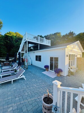 A two-story building with a balcony, outdoor seating, and a small shed.