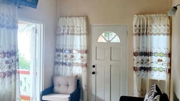 A living room with a ceiling fan, a sofa, a chair, and a door.