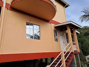 A two-story building with a red and beige color scheme, a balcony, and a staircase leading to the upper floor.