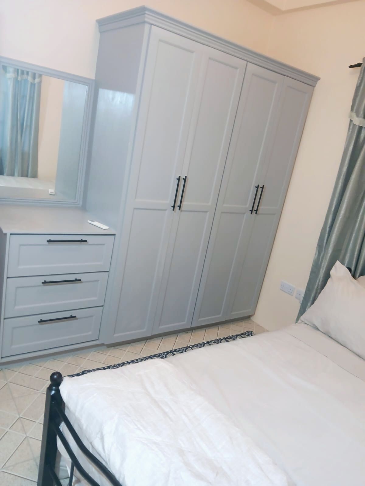 A bedroom with a bed, a wardrobe, a dresser, and a mirror.