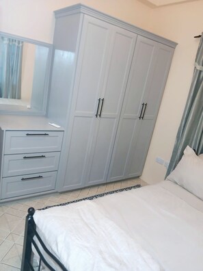 A bedroom with a bed, a wardrobe, a dresser, and a mirror. - Fully furnished 2-bedroom apartment with AC in Saint George (Saint George)