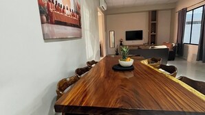 A conference room with a long wooden table, chairs, a TV, and a painting on the wall. - Casa Confort Ahuachapan/ 3 suites with AC & Smart Tvs (Ahuachapan centro)