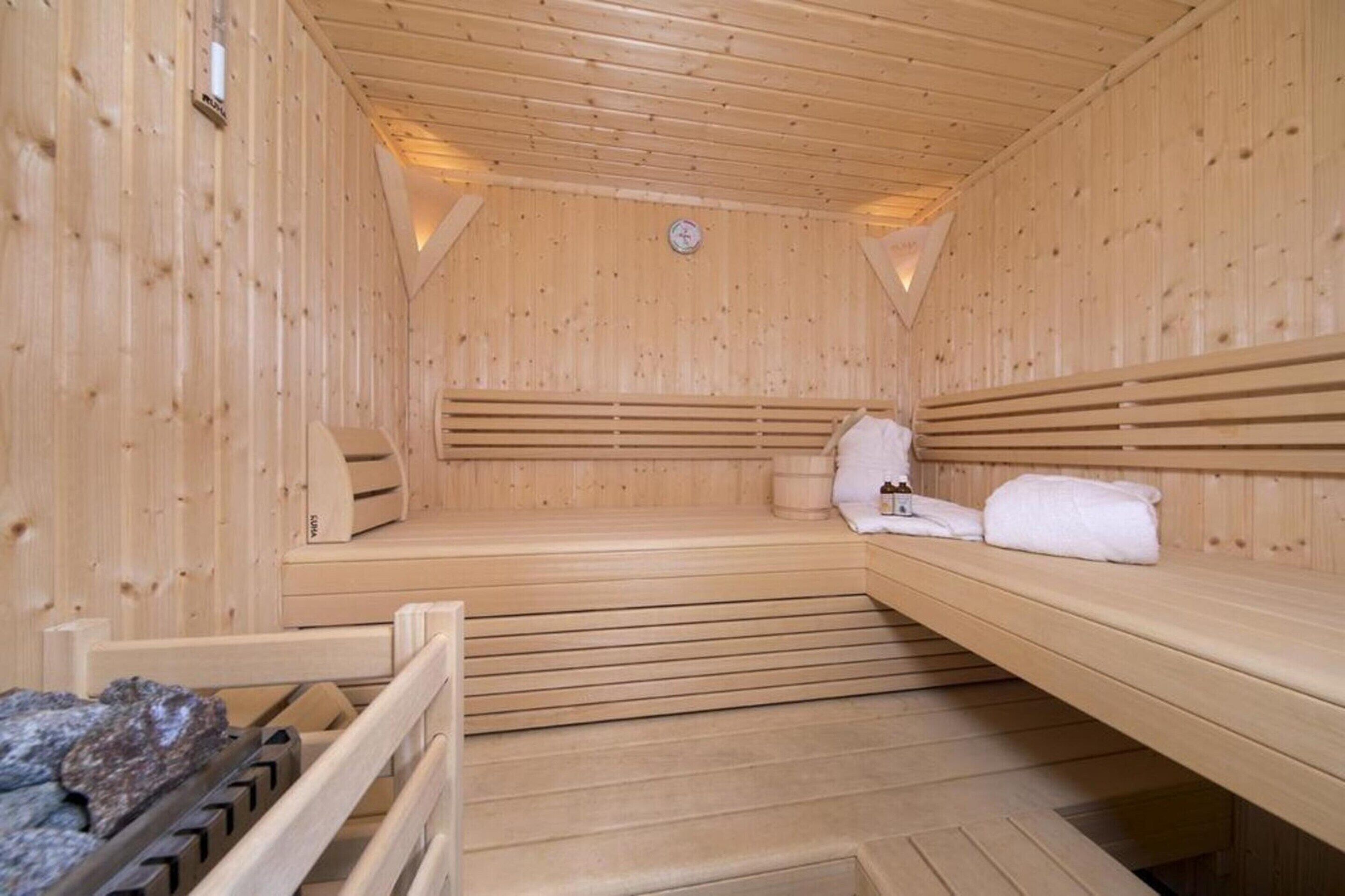 Un sauna en bois, avec des bancs et une banquette, une serviette et un radiateur.
