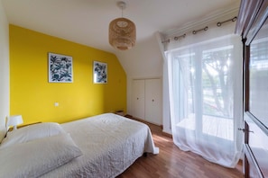 A bedroom with a bed, a window with curtains, and two wall-mounted pictures.