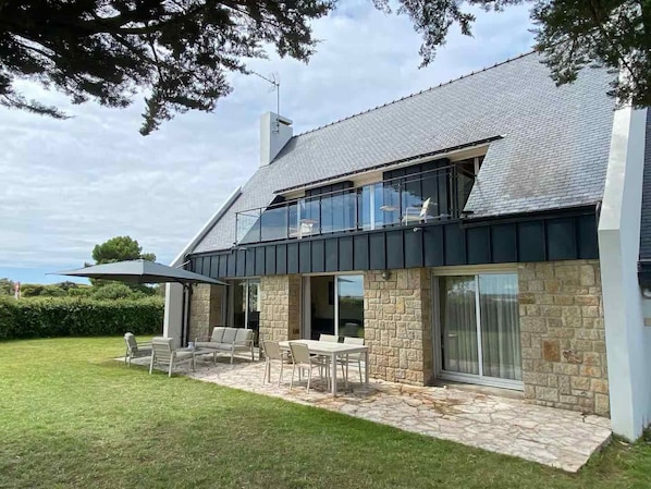 A modern house with a stone exterior, a balcony, and a patio with outdoor furniture.