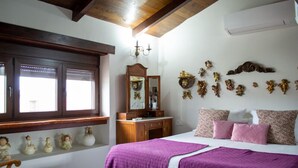 A bedroom with a bed, a dresser, a mirror, a shelf with figurines, and a window with blinds.