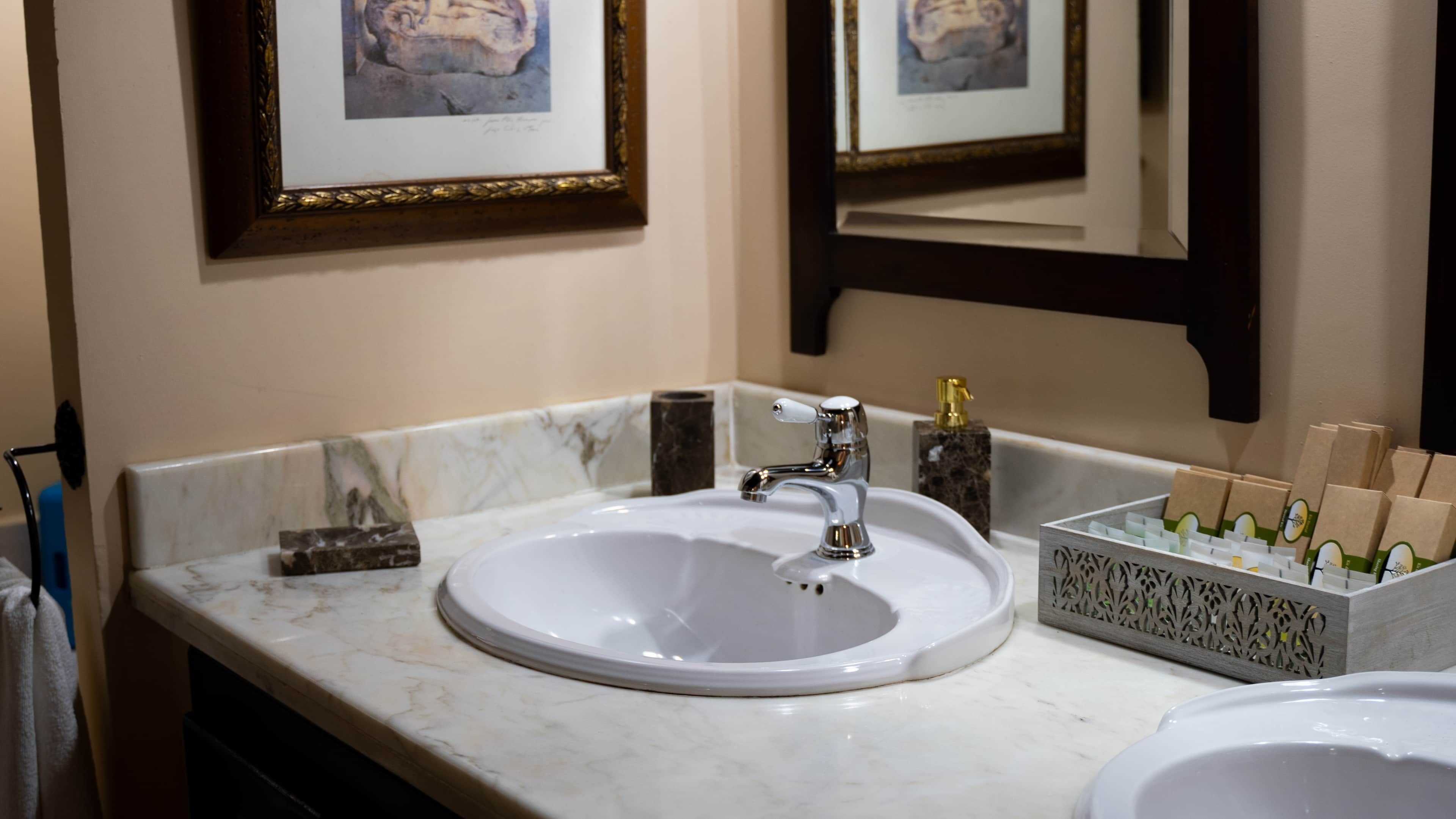 A bathroom with a white sink, a mirror, and a soap dispenser.