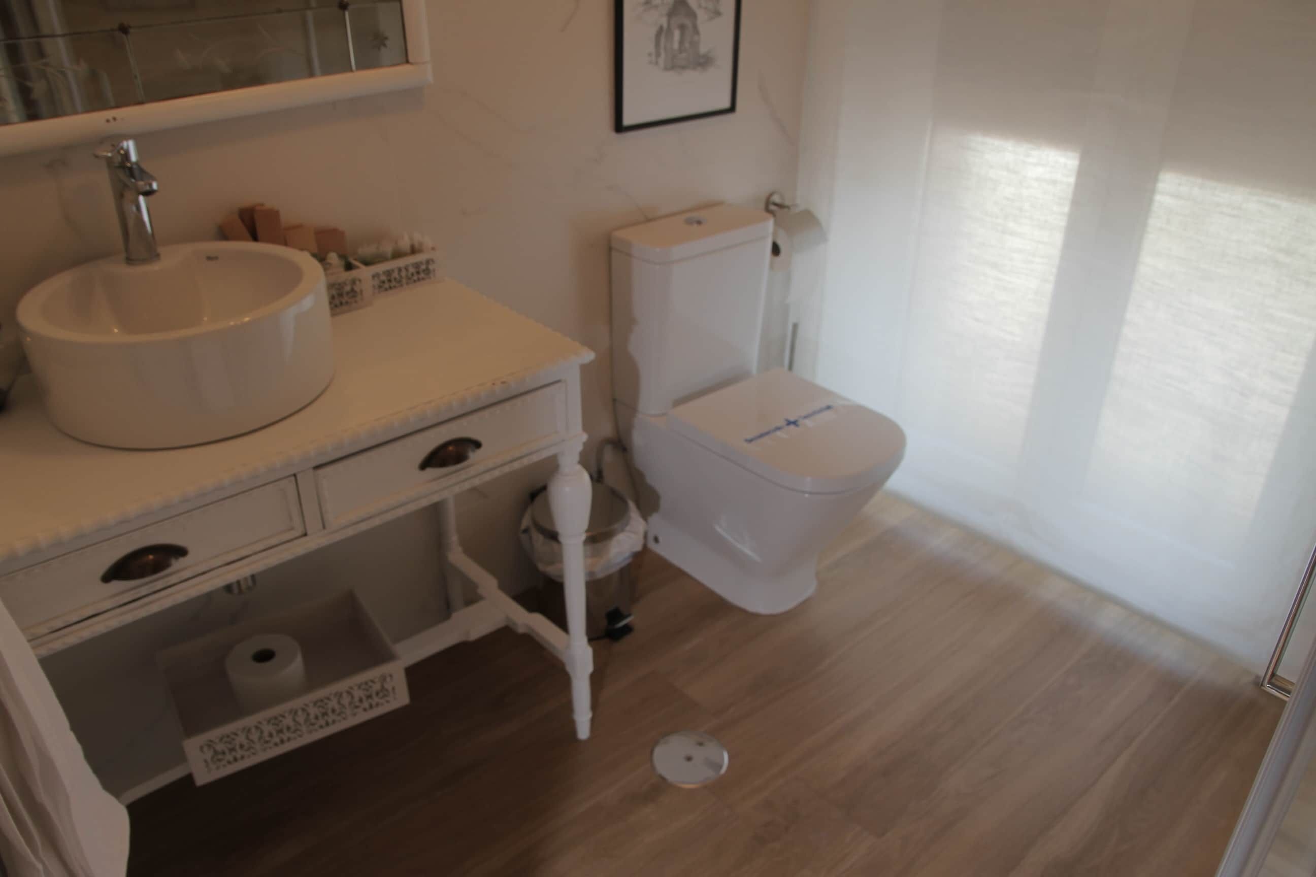 Een badkamer met een wit wastafel, toilet en een spiegel boven de wastafel.