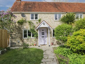 A stone house with a red-tiled roof, a white door, and a small garden with a stone pathway. - Lavender Cottage (Gillingham)