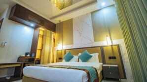 Ein Hotelzimmer mit einem großen Bett, Nachttischen, einem Schreibtisch, einem Stuhl, einem Spiegel, einem Fenster mit Vorhängen und einer Deckenleuchte.
