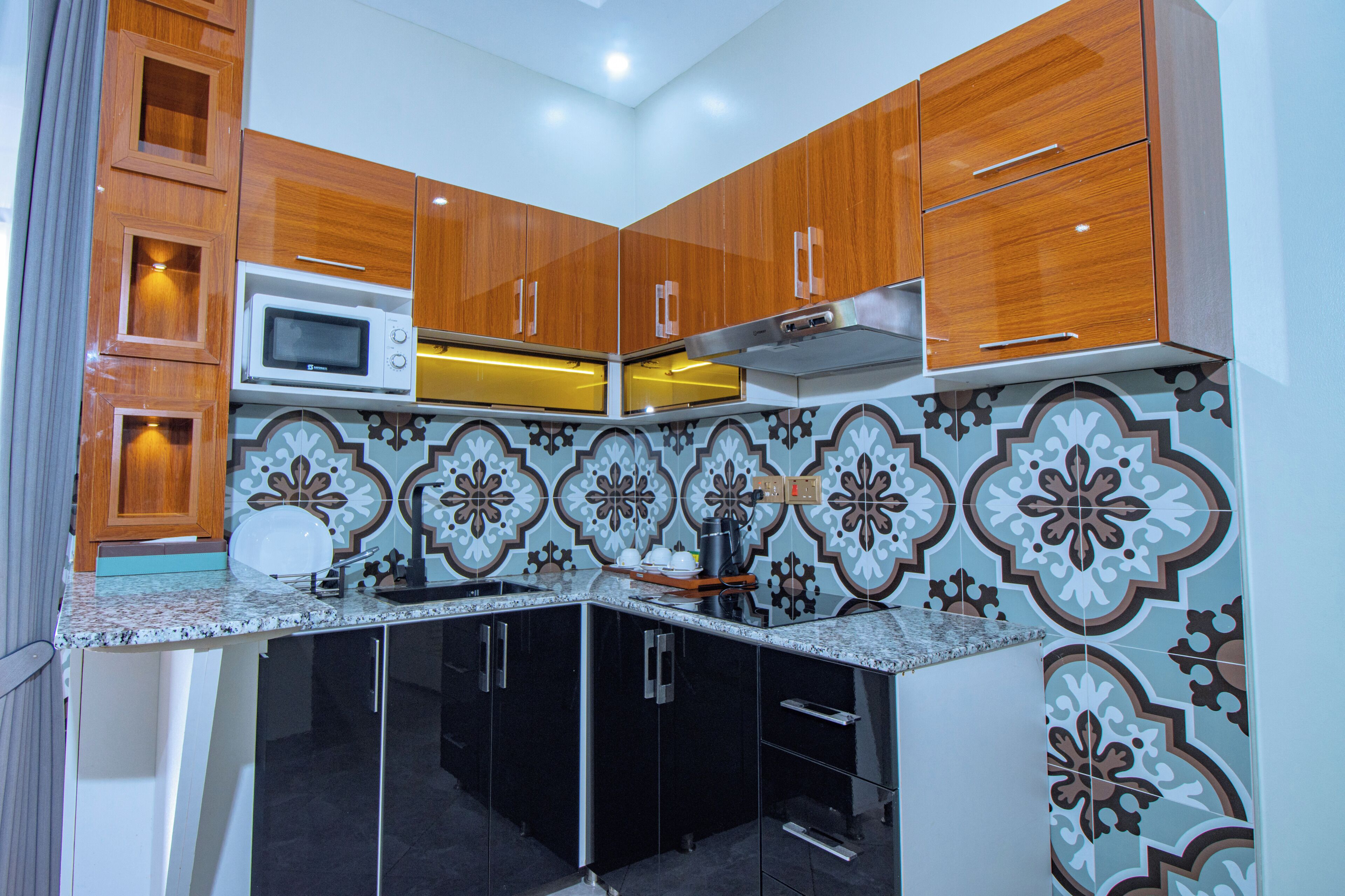 A kitchen with wooden cabinets, a microwave, and a patterned backsplash.