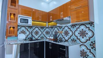 A kitchen with wooden cabinets, a microwave, and a patterned backsplash.