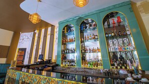 Eine Bar mit einer Theke, Flaschenregalen und hängenden Lampen.