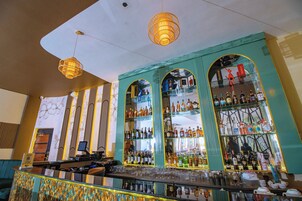 Zona de bar con mostrador, estantes de botellas y luces colgantes.