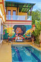Un área de piscina con un mural, una banca y vistas al cielo.