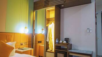 A hotel room with a bed, bedside table, a mirror, a desk, and a wardrobe.